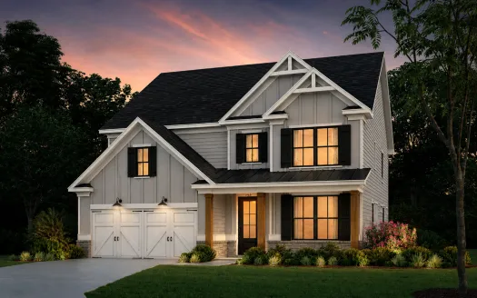 Modern two-story gray house with black shutters, warm interior lights, and a landscaped front yard at sunset