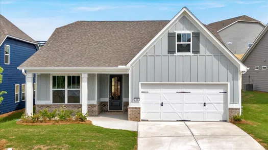 Modern single-story gray house with white garage door, front porch, brick accents, and landscaped yard under blue sky
